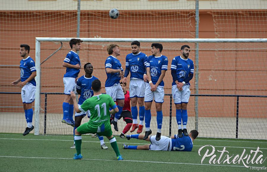 La barrera del San Fernando CD 'B' salta para intentar despejar una falta lanzada por el Villamartín.