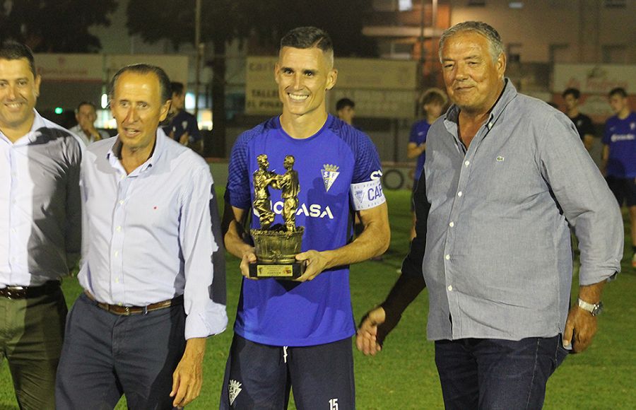 Juanmi Callejón muestra el trofeo de campeón del XII Trofeo de la Vendimia en presencia del alcalde de Chiclana, José María Román, el presidente del Chiclana, Juan Luis Rojo y el consejero del San Fernando CD, Pedro Ramírez