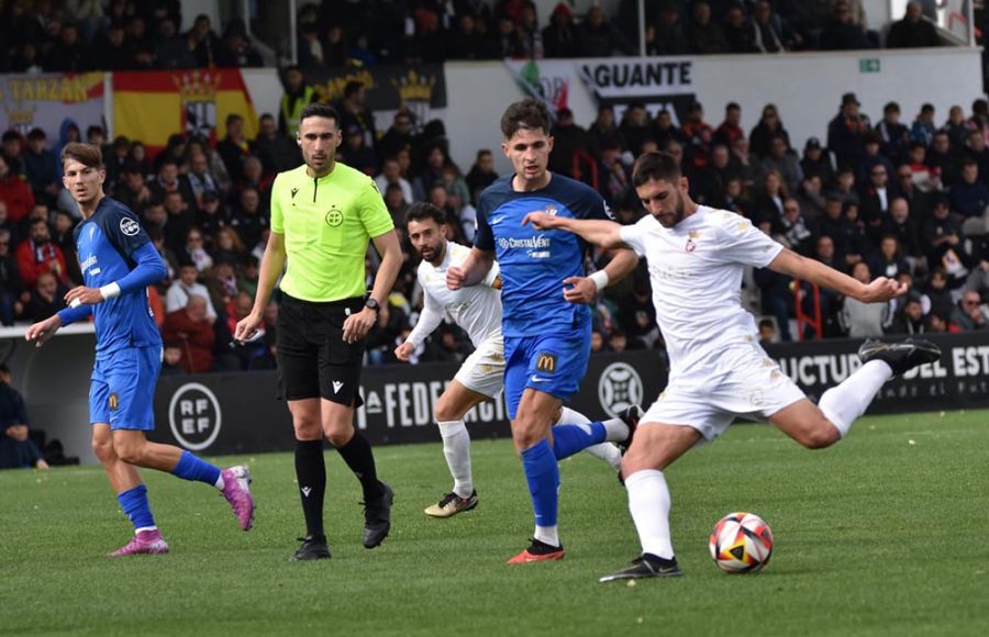 El lateral de la AD Ceuta, Redru dispara a portería ante la mirada de Unai Naveira, Yerai Dávila, su compañero Ñito González y el colegiado.