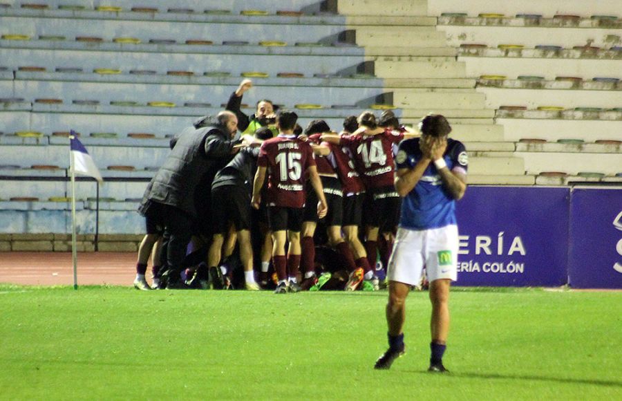 Los jugadores y componentes del banquillo de la AD Mérida celebran el gol del triunfo ante la desolación de Dani Aquino.